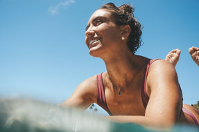 SURFER GIRL PADDLING SMILING WEARING JEWERLY