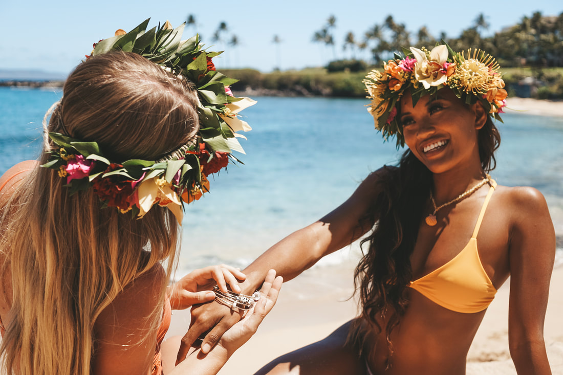 TWO GIRLS SHARING JEWELRY AND FUN IN THE BEACH OF HAWAII DURING A PHOTOSHOOT FOR PRODUCT PHOTOGRAPHY
