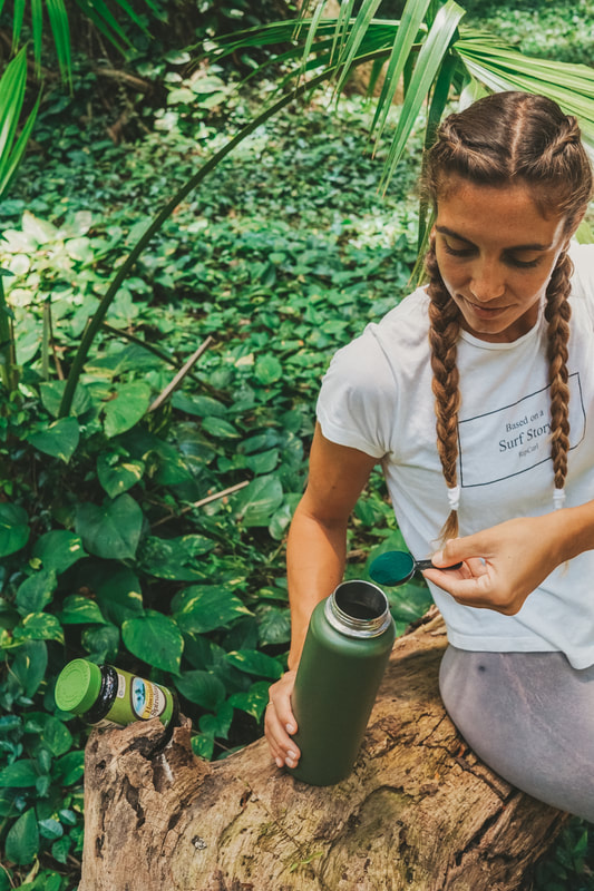 HIKER FILLING HER WATER BOTTLE WITH SPIRULINA TO GET SOME ENERGY AND FINISH THE JUNGLE EXPLORATION